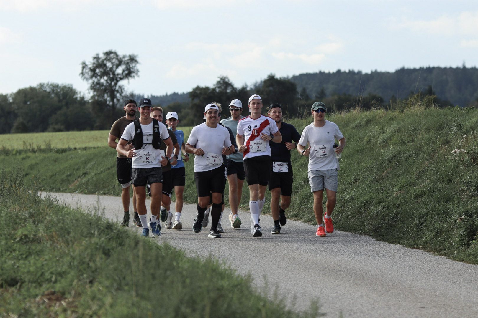 Läufergruppe auf dem geschwungenen Weg durch die offene Landschaft, 2026