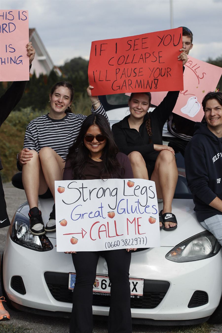 Fans auf der Motorhaube mit Schildern wie Strong Legs, Great Glutes, Call me